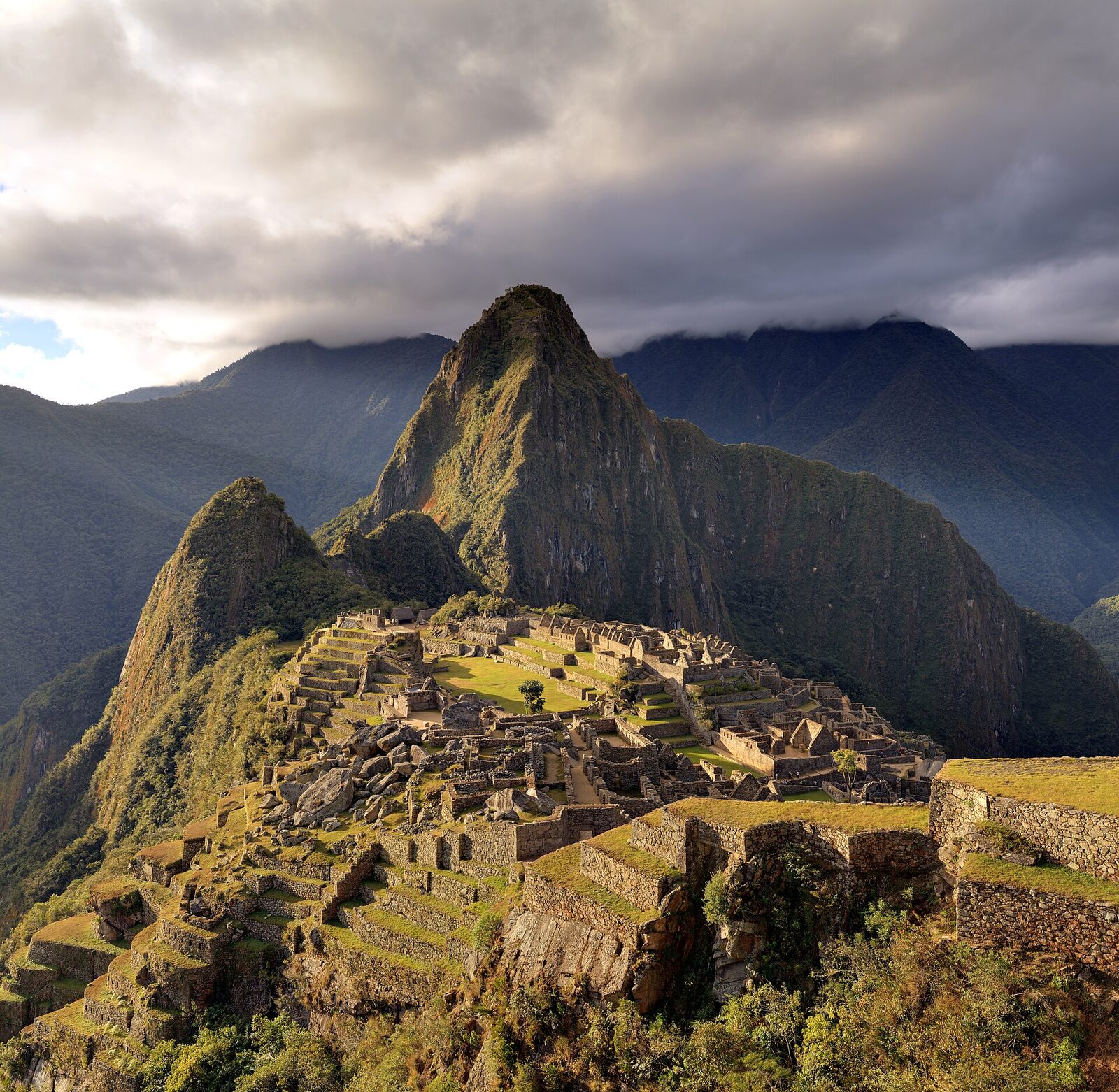 Machu Picchu citadel in golden storm light with Huayna Picchu behind